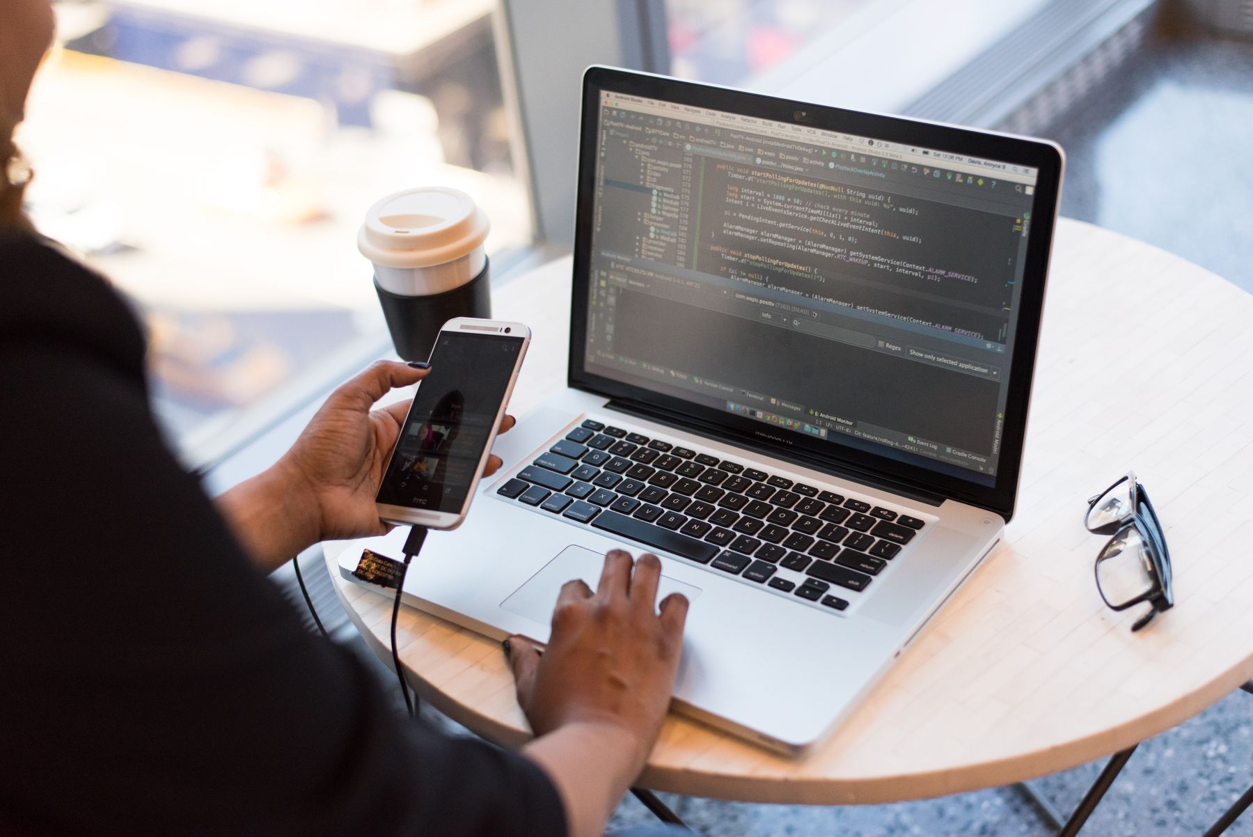 Developer working on a laptop beside a phone at night